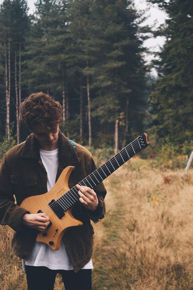 Composer und Musiker Dan James Griffin mit seiner Strandberg 7-String Gitarre mit Fanned Frets. Im Hintergrund ein Wald.
