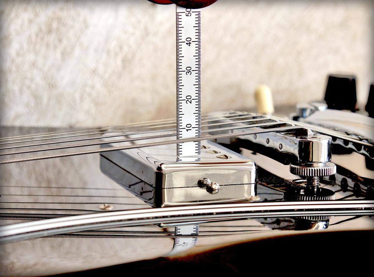 Gitarre Einstellen: Die Höhe von der Pickup-Kappe bis zur Unterseite der Saite messen.