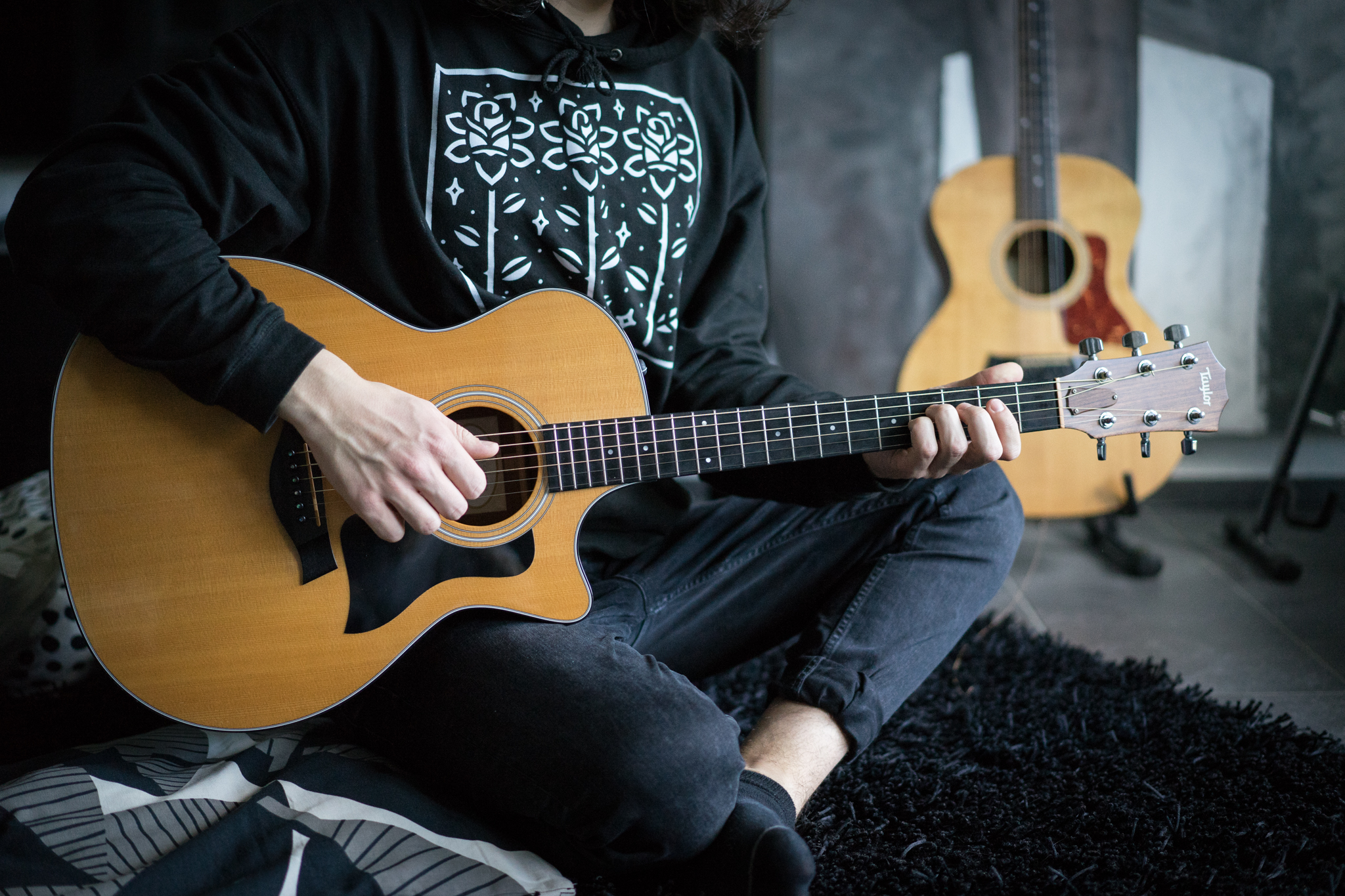 Momentaufnahme einer Taylor Guitars 314CE Akustikgitarre. Im Hintergrund steht eine Taylor Guitars 214 Akustikgitarre. Foto von Julius Haring.